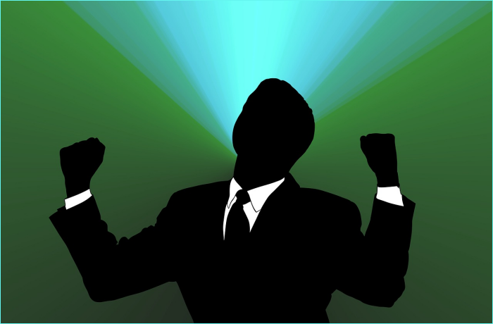 Silhouette of a business person celebrating with raised fists against a colorful background.